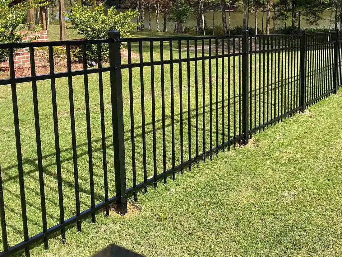 Black aluminum fence enclosing a green residential yard