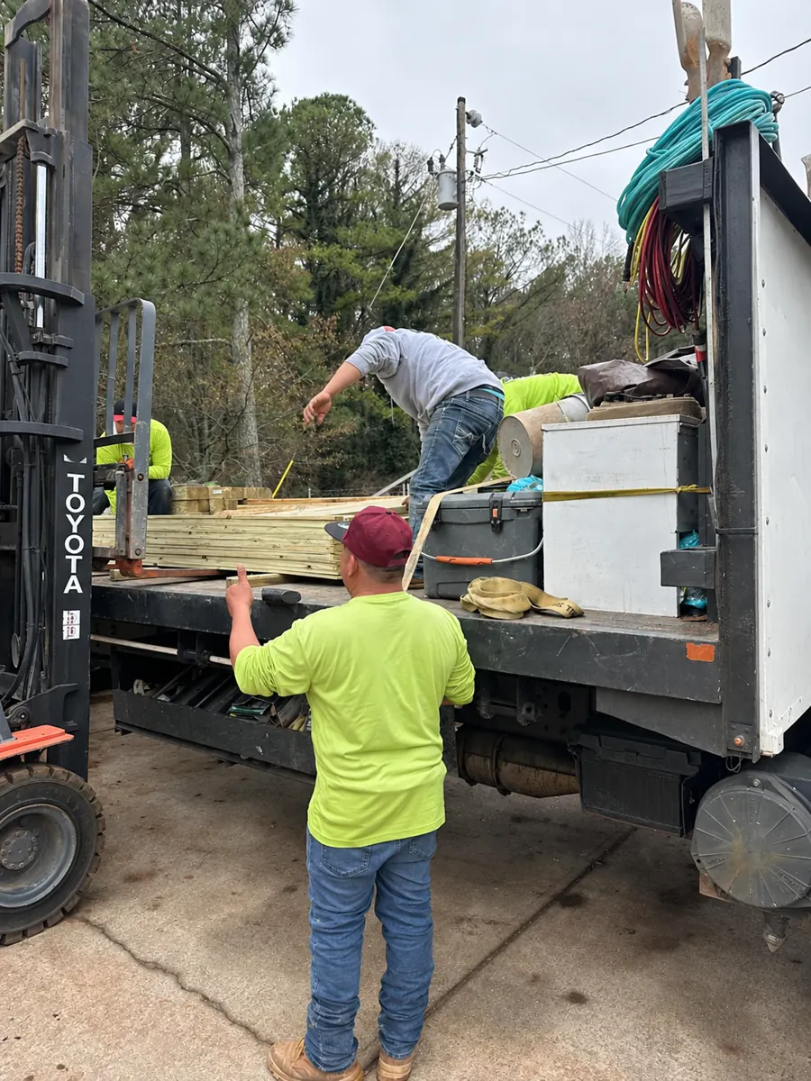 Crew preparing fence lumber and loading a work truck