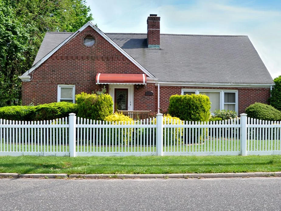 White picket fence beside a brick home