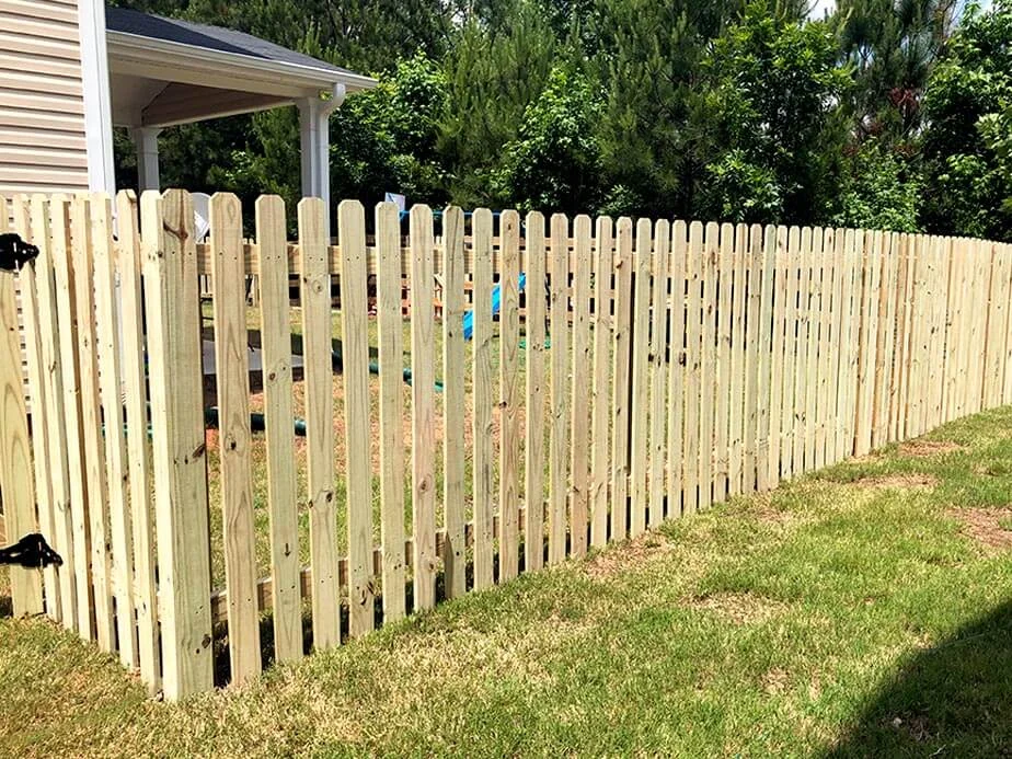 Wood picket fence with an open green backdrop