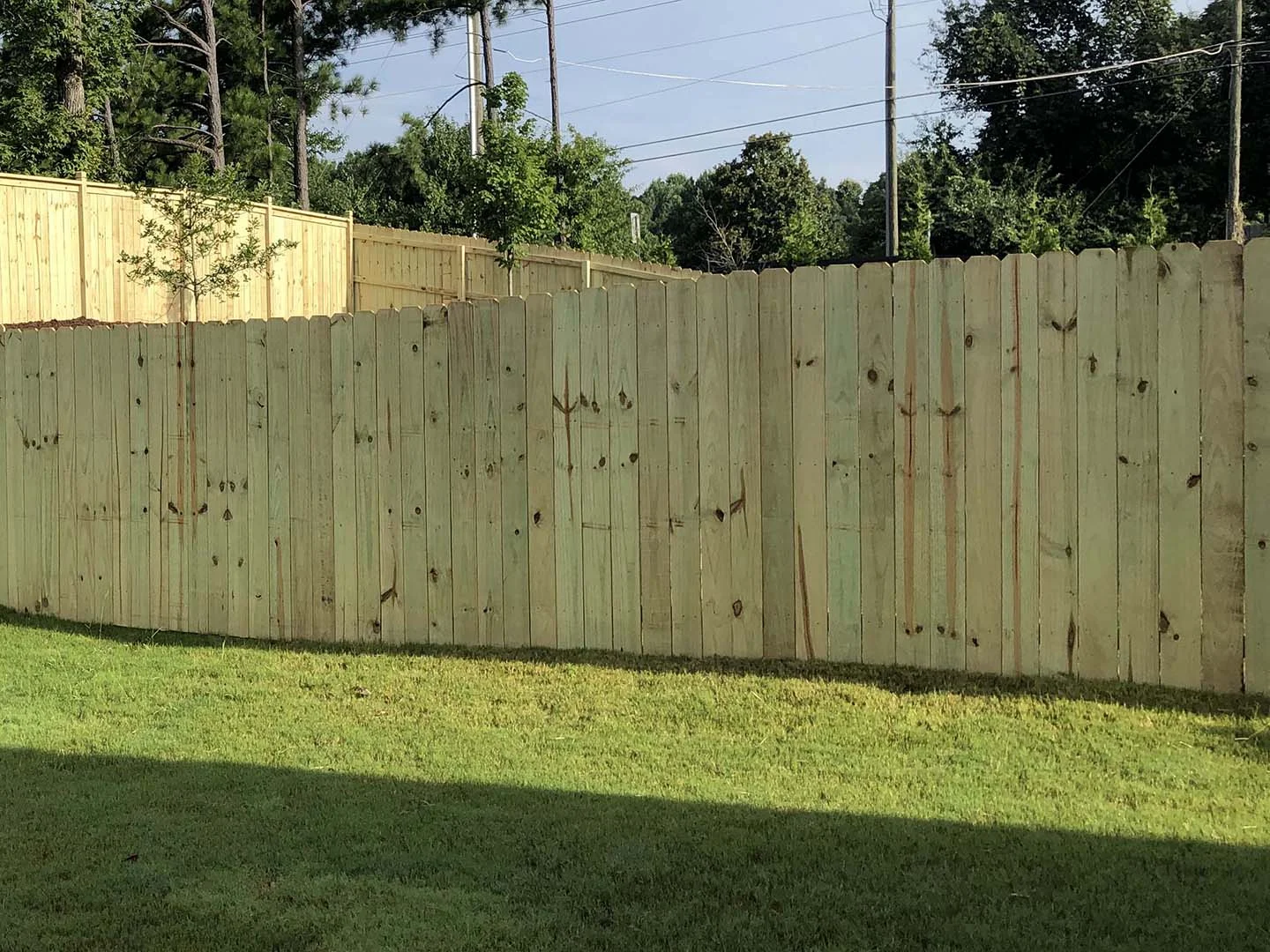 Dog ear wood privacy fence along a lawn