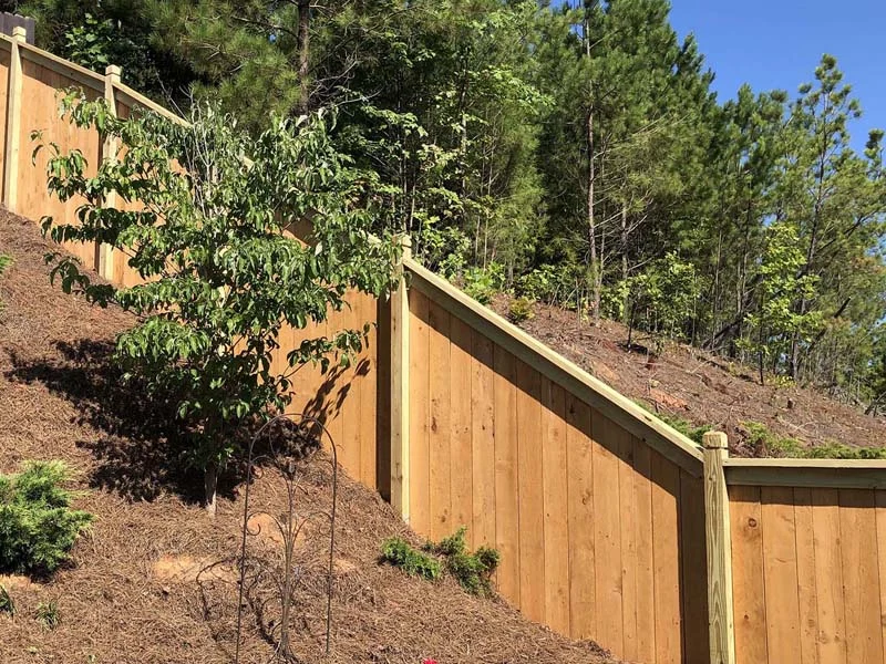 Capped wood privacy panels on a slope