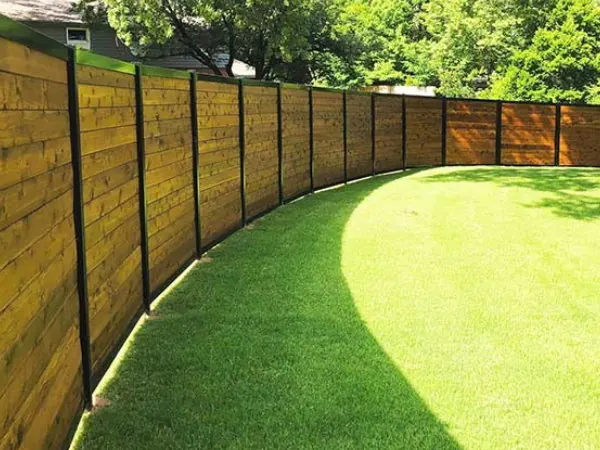Wood privacy panels framed in black metal following a curved yard